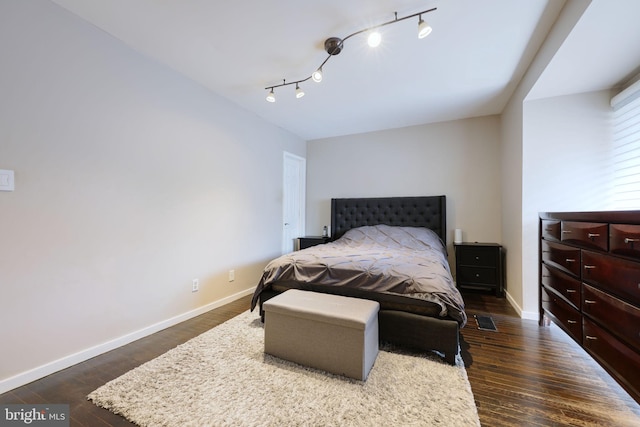 bedroom with dark hardwood / wood-style flooring and track lighting