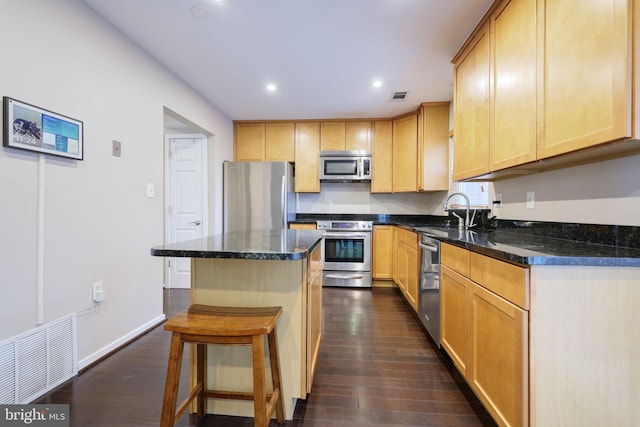 kitchen featuring light brown cabinetry, sink, a center island, appliances with stainless steel finishes, and dark hardwood / wood-style flooring