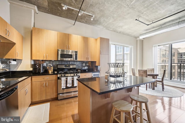 kitchen with a center island, tasteful backsplash, sink, stainless steel appliances, and a breakfast bar area