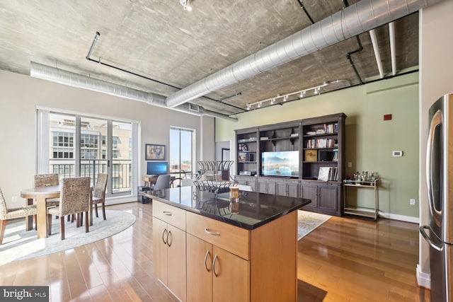 kitchen featuring light wood-type flooring, a kitchen island, stainless steel refrigerator, and plenty of natural light