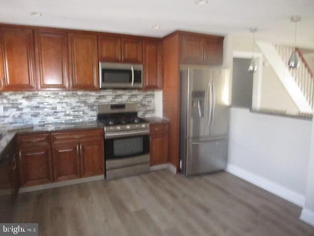 kitchen with pendant lighting, hardwood / wood-style floors, decorative backsplash, and appliances with stainless steel finishes