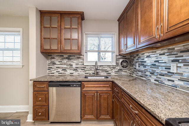 kitchen featuring tasteful backsplash, dishwasher, sink, and light stone countertops