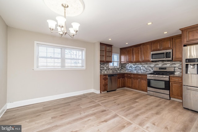 kitchen featuring pendant lighting, sink, backsplash, stainless steel appliances, and a notable chandelier