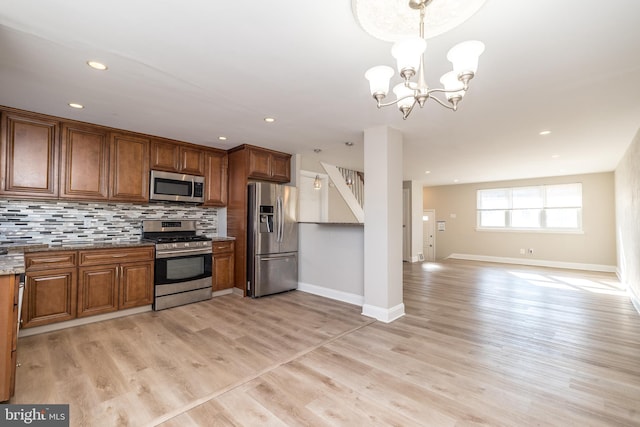 kitchen featuring appliances with stainless steel finishes, decorative light fixtures, backsplash, a chandelier, and light hardwood / wood-style flooring