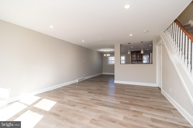 unfurnished living room with a chandelier and light hardwood / wood-style flooring