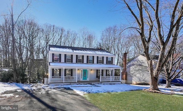 colonial inspired home with covered porch and a lawn