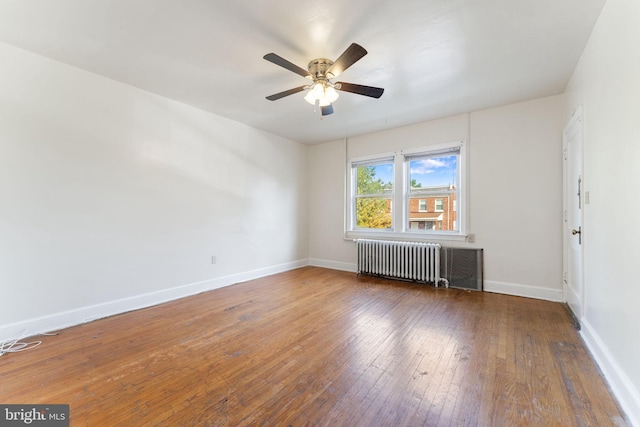 empty room with ceiling fan, dark hardwood / wood-style floors, and radiator heating unit