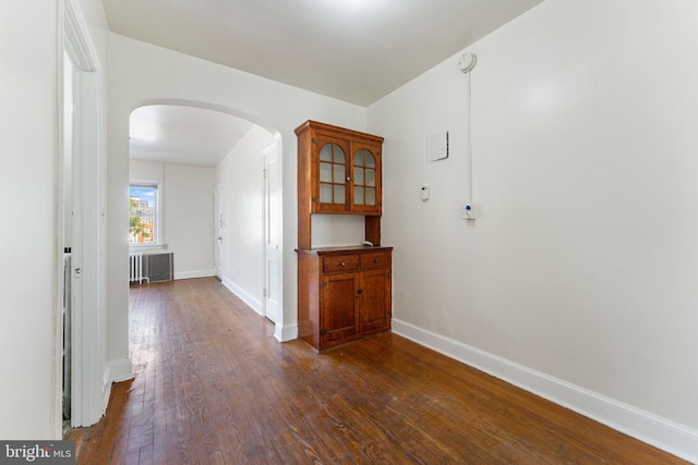 corridor with dark hardwood / wood-style flooring and radiator