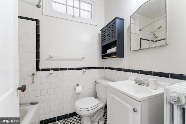 bathroom with toilet, vanity, and tile walls