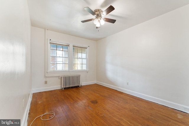 empty room with hardwood / wood-style floors, radiator, and ceiling fan