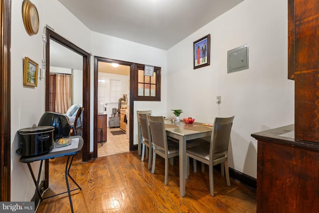 dining space with electric panel and wood-type flooring