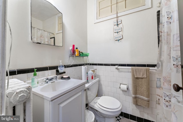 bathroom featuring vanity, toilet, and tile walls