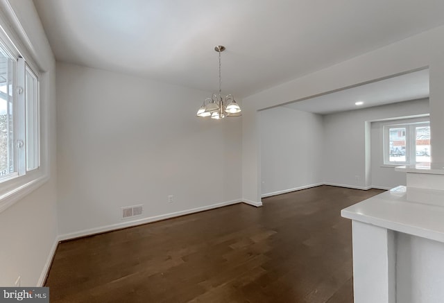 unfurnished dining area with a chandelier and dark wood-type flooring