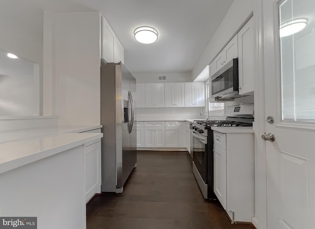 kitchen with white cabinetry, appliances with stainless steel finishes, and dark hardwood / wood-style flooring