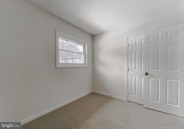 unfurnished bedroom featuring light carpet and a closet