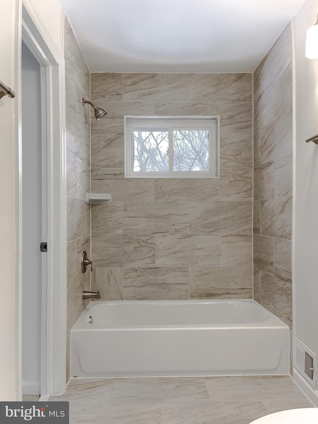 bathroom featuring toilet and tiled shower / bath