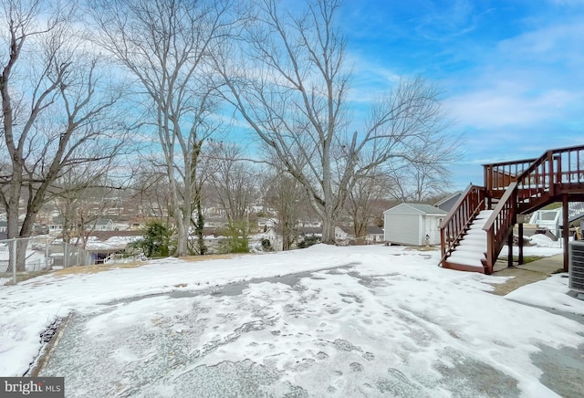 snowy yard with central AC unit and a storage shed