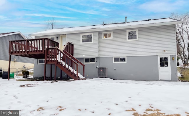 snow covered property featuring central AC unit and a wooden deck