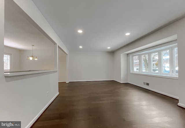 unfurnished room with a chandelier and dark hardwood / wood-style floors