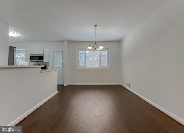 unfurnished dining area with a chandelier and dark hardwood / wood-style flooring