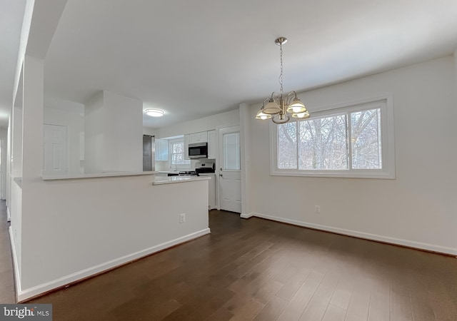 kitchen featuring appliances with stainless steel finishes, white cabinets, decorative light fixtures, kitchen peninsula, and an inviting chandelier