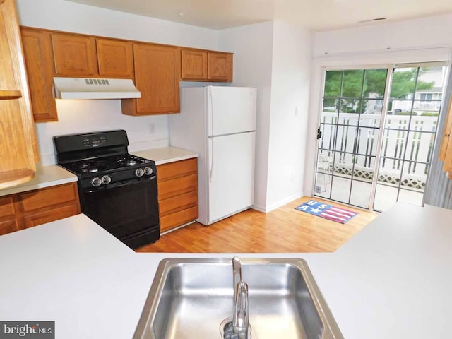 kitchen with black range with gas stovetop, white refrigerator, sink, and light hardwood / wood-style flooring