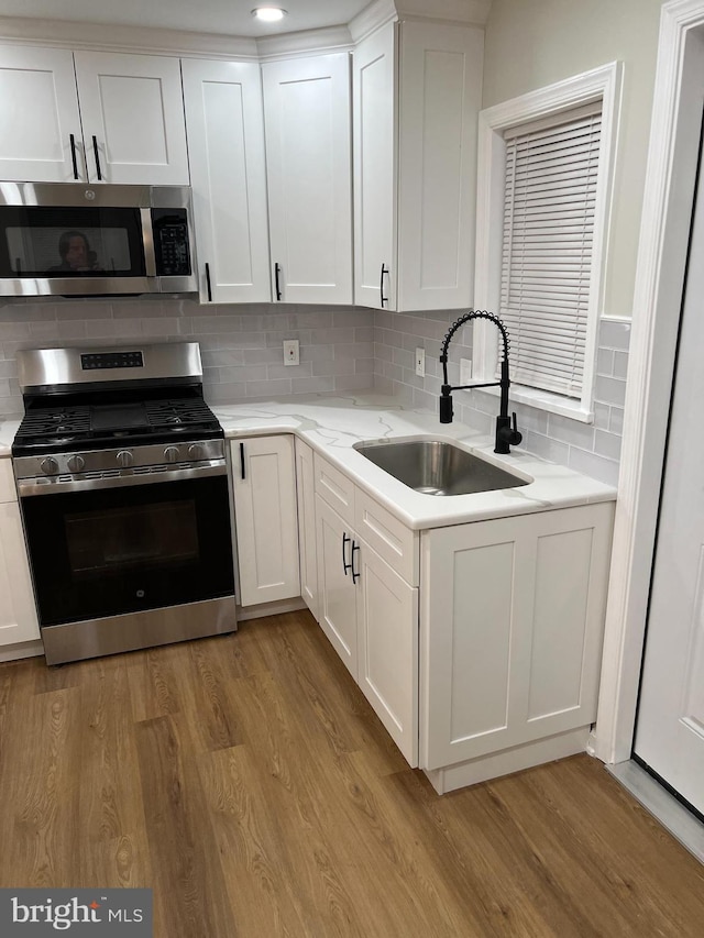 kitchen with backsplash, sink, white cabinets, and appliances with stainless steel finishes