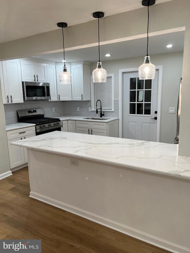 kitchen featuring sink, stainless steel appliances, white cabinetry, and light stone counters