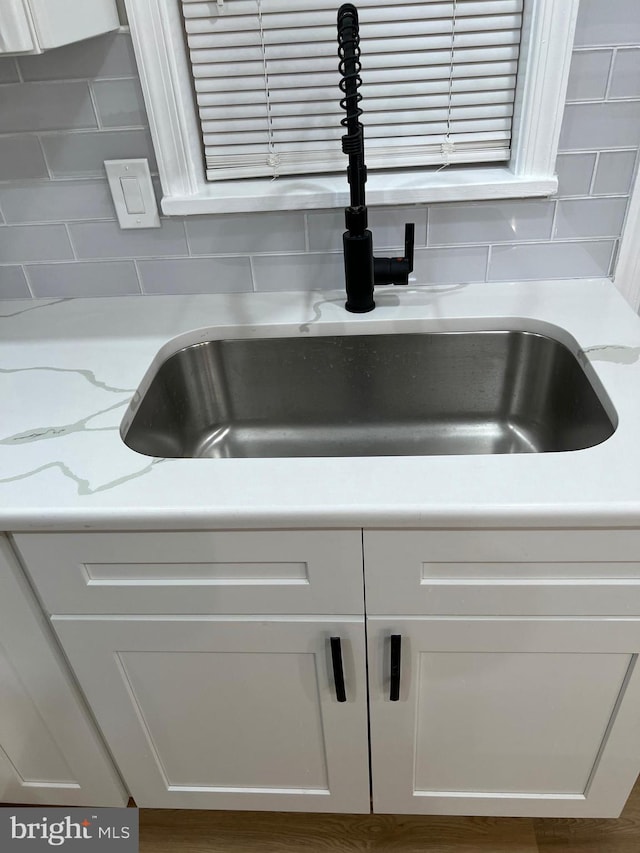 room details featuring sink, backsplash, and white cabinets