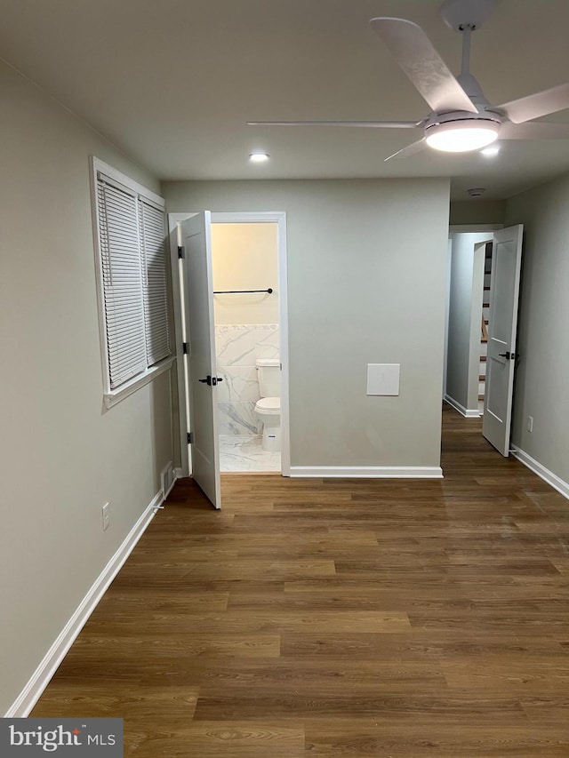 unfurnished bedroom featuring ensuite bathroom, dark hardwood / wood-style floors, and ceiling fan