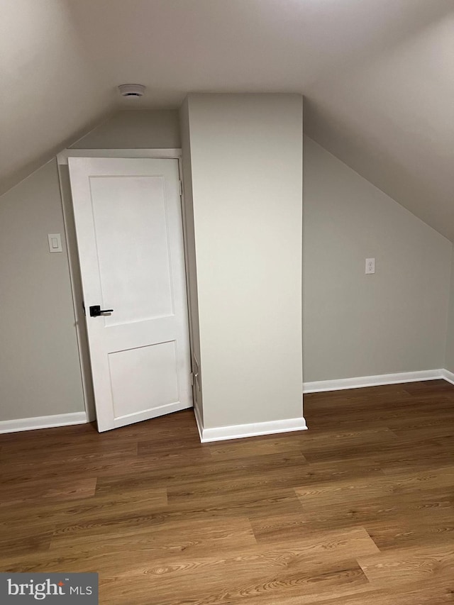 bonus room with light wood-type flooring and vaulted ceiling