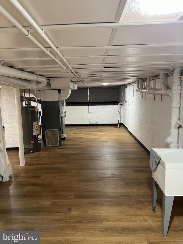 basement featuring wood-type flooring and water heater