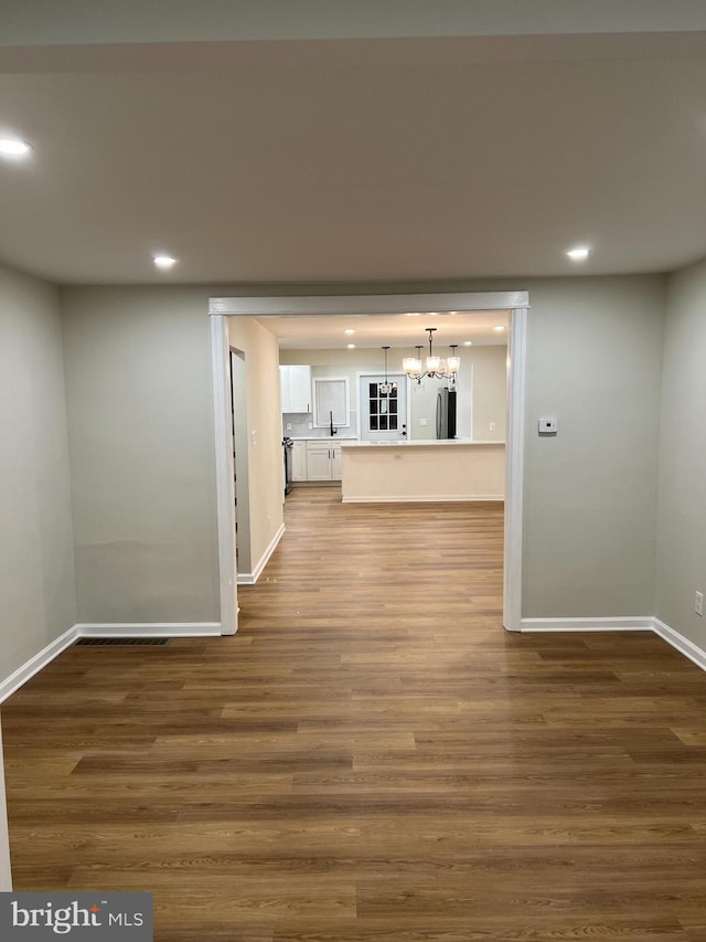 hallway featuring dark wood-type flooring and a notable chandelier