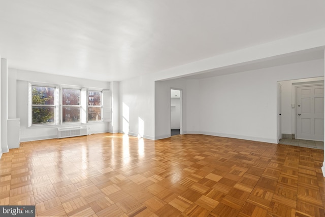 unfurnished living room featuring light parquet flooring and radiator