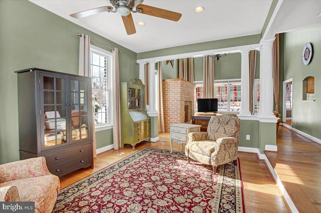 sitting room with decorative columns, light hardwood / wood-style floors, and ceiling fan