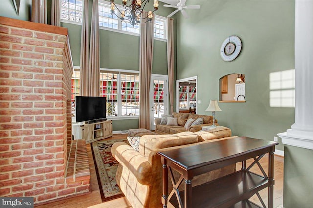 living room featuring a high ceiling, plenty of natural light, decorative columns, and light hardwood / wood-style flooring