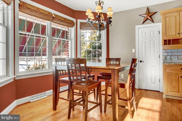 dining space with a notable chandelier and light wood-type flooring