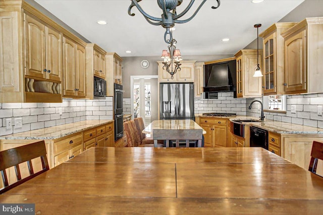 kitchen with pendant lighting, light stone counters, black appliances, and custom range hood