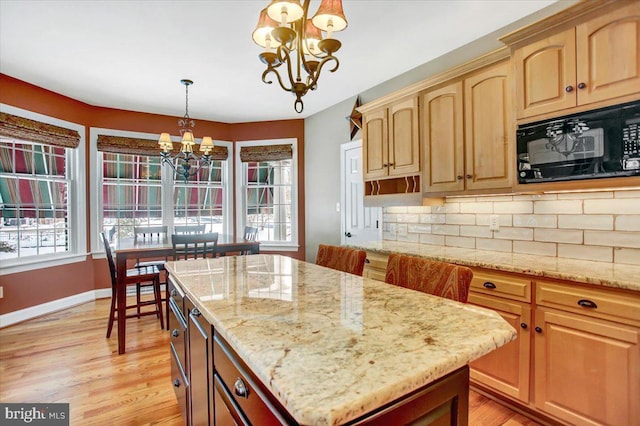 kitchen with hanging light fixtures, tasteful backsplash, a notable chandelier, light stone countertops, and a kitchen island