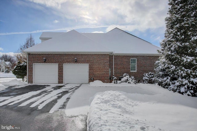 snow covered property with a garage