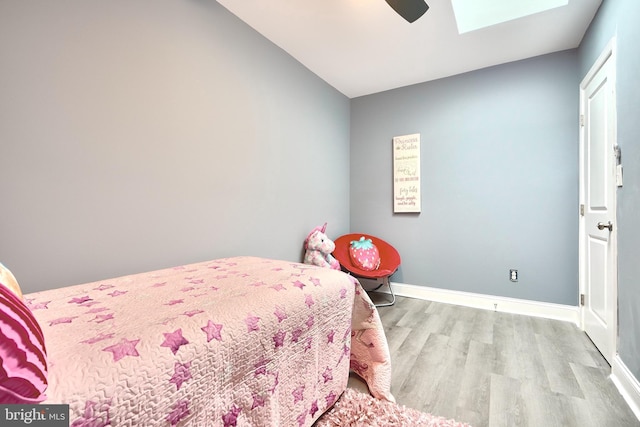 bedroom featuring a skylight, ceiling fan, and light wood-type flooring