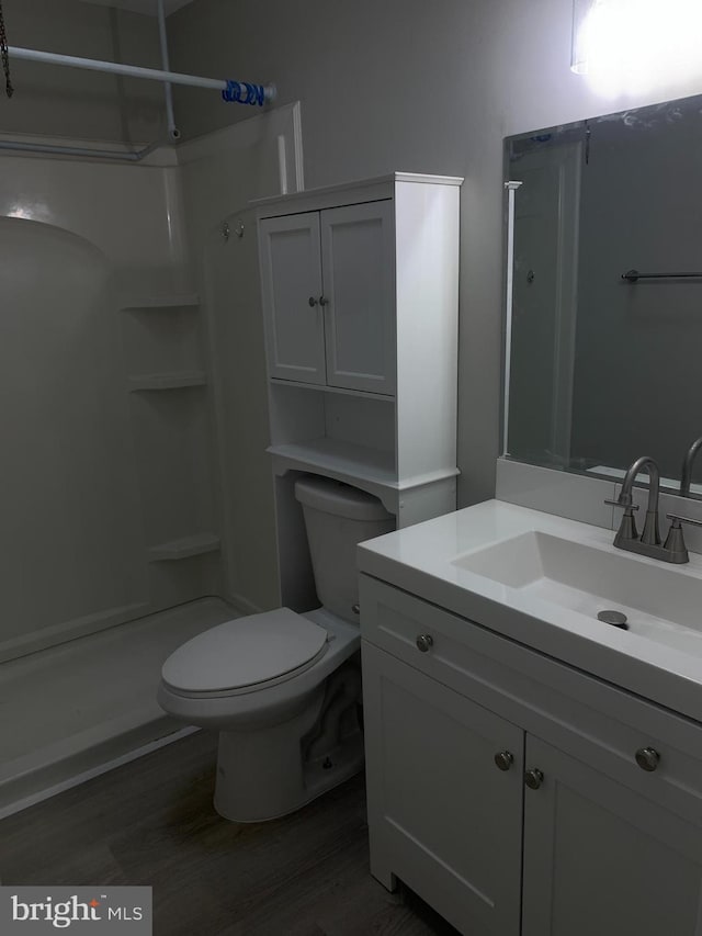 bathroom featuring hardwood / wood-style floors, toilet, vanity, and walk in shower