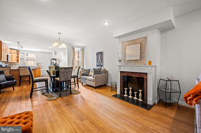 living room with a fireplace, an inviting chandelier, and light hardwood / wood-style flooring