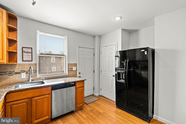 kitchen with stainless steel dishwasher, black fridge with ice dispenser, sink, light hardwood / wood-style floors, and decorative backsplash