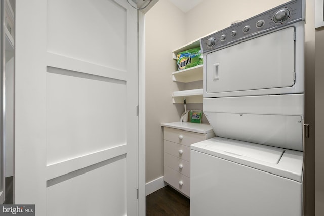 laundry area with stacked washer / drying machine and dark hardwood / wood-style flooring