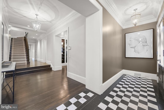 foyer entrance with ornamental molding, an inviting chandelier, and dark wood-type flooring