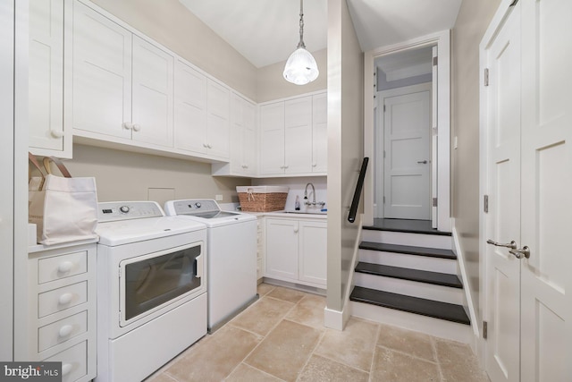 clothes washing area with sink, washing machine and clothes dryer, and cabinets