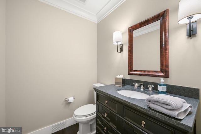 bathroom with toilet, vanity, and ornamental molding