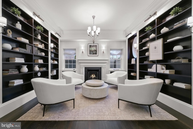 sitting room featuring crown molding, built in features, dark wood-type flooring, and a notable chandelier