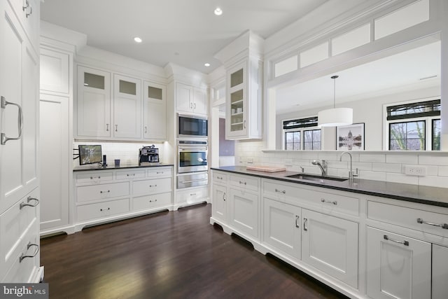 kitchen featuring sink, decorative light fixtures, white cabinets, oven, and black microwave